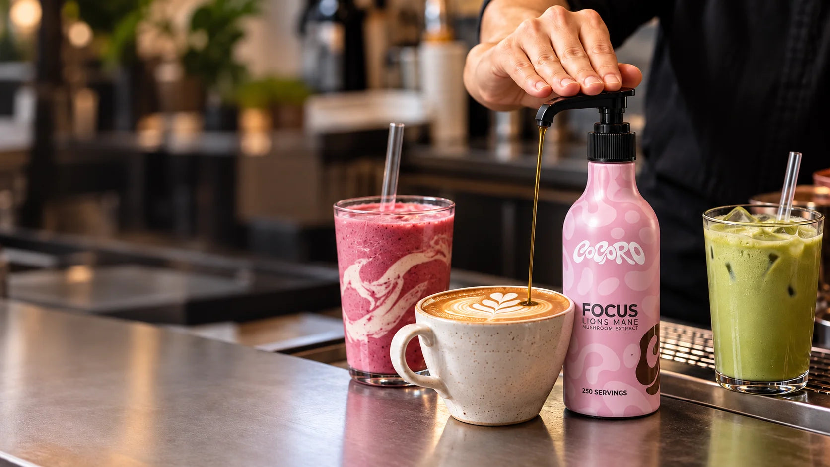A barista adding one pump of COCORO Focus to a latte, with a smoothie and matcha beside it